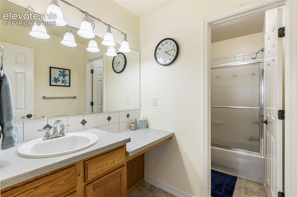 Image 15 of 28: Bathroom featuring a vanity with wood-finish cabinetry, a single basin sink