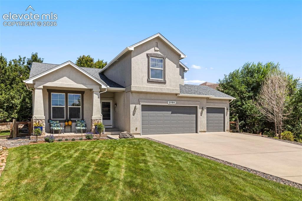Image 2 of 28: Stucco exterior with stone accents, a covered front porch, and a two-car ga