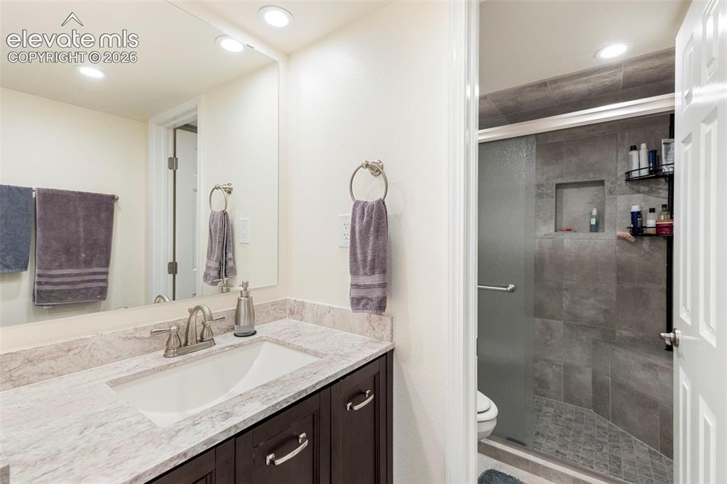 Image 24 of 28: Vanity with undermount sink and stone countertop, dark wood-finish cabinetr
