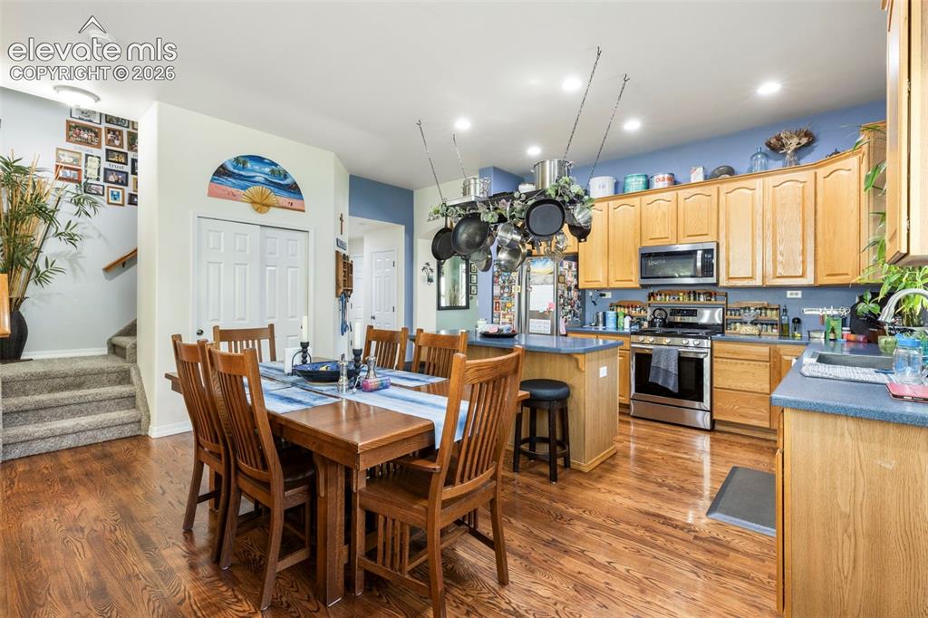 Image 6 of 28: Kitchen and dining area featuring wood-finish flooring, light wood cabinetr