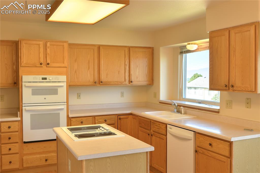 Image 10 of 48: Kitchen featuring white appliances, light countertops, and light brown cabi