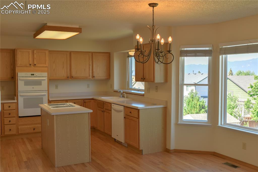 Image 11 of 48: Kitchen featuring light brown cabinets, light wood-type flooring, white app