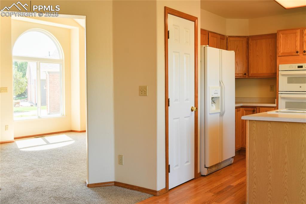 Image 12 of 48: Kitchen featuring white appliances, light countertops, brown cabinets, ligh