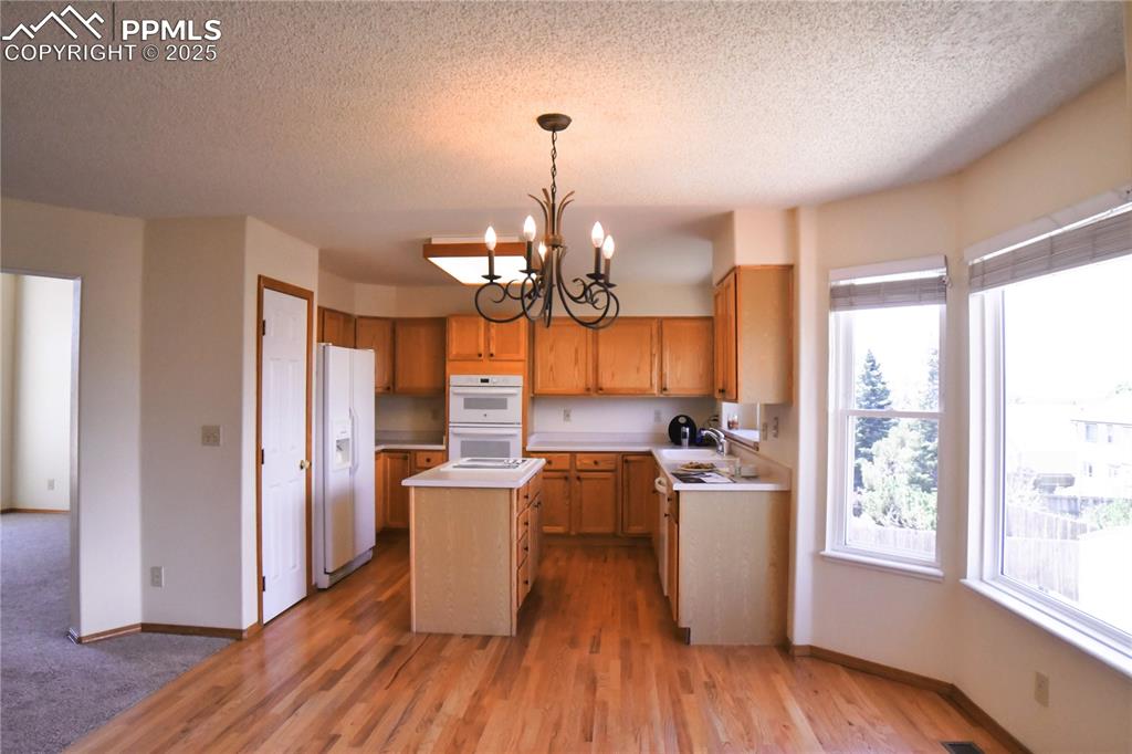 Image 13 of 48: Kitchen featuring a chandelier, a center island, light countertops, white a