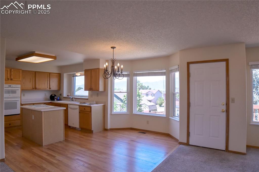 Image 14 of 48: Kitchen featuring a chandelier, light countertops, a center island, a textu