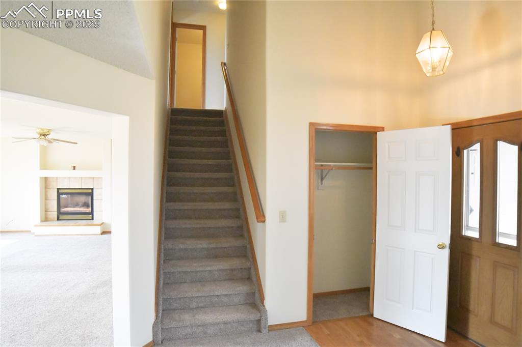 Image 22 of 48: Entryway featuring stairway, ceiling fan, a tiled fireplace, and carpet