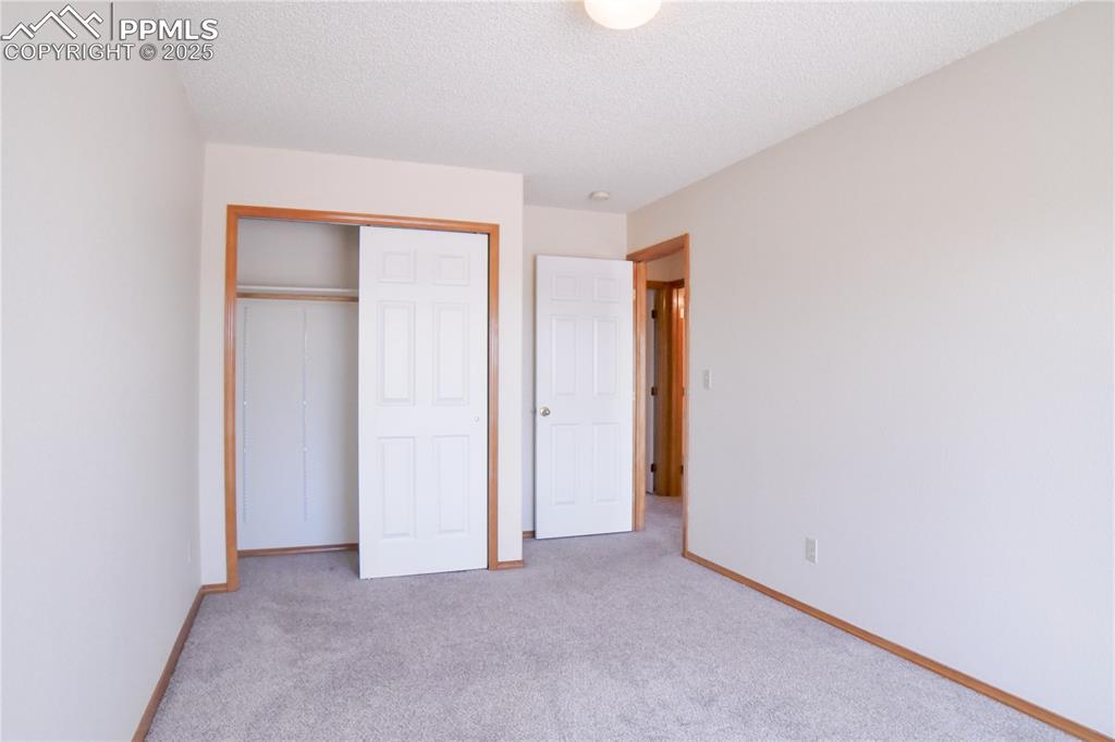 Image 28 of 48: Unfurnished bedroom with carpet, a closet, and a textured ceiling