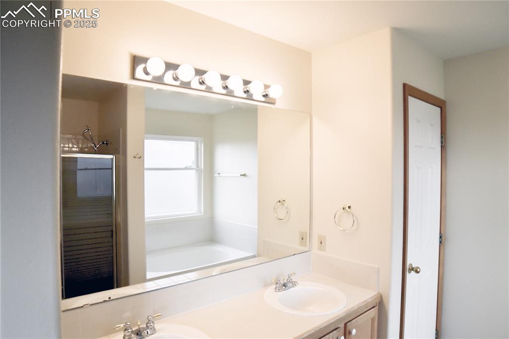 Image 29 of 48: Bathroom with double vanity, a garden tub, and a shower