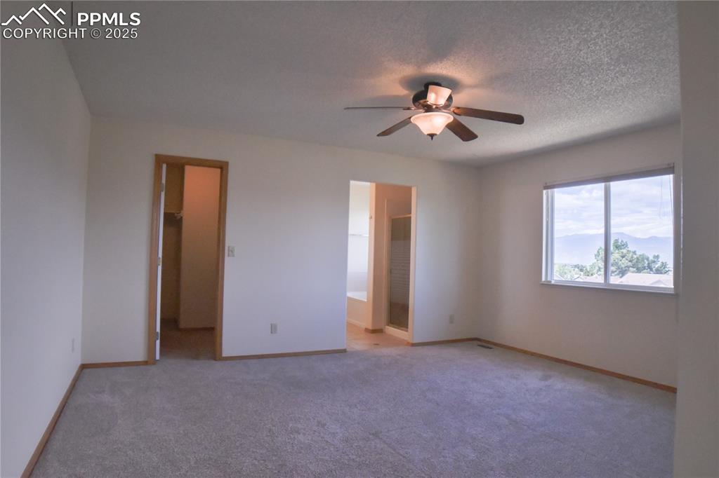 Image 30 of 48: Unfurnished bedroom featuring light carpet, a walk in closet, ceiling fan, 
