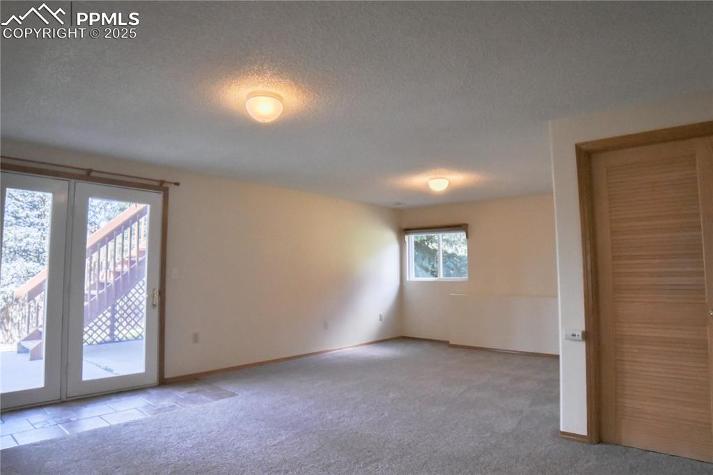 Image 42 of 48: Empty room with carpet, a textured ceiling, and french doors