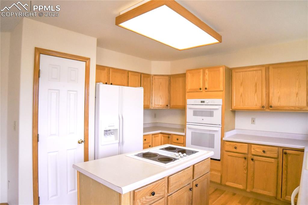 Image 9 of 48: Kitchen featuring white appliances, light countertops, a kitchen island, an