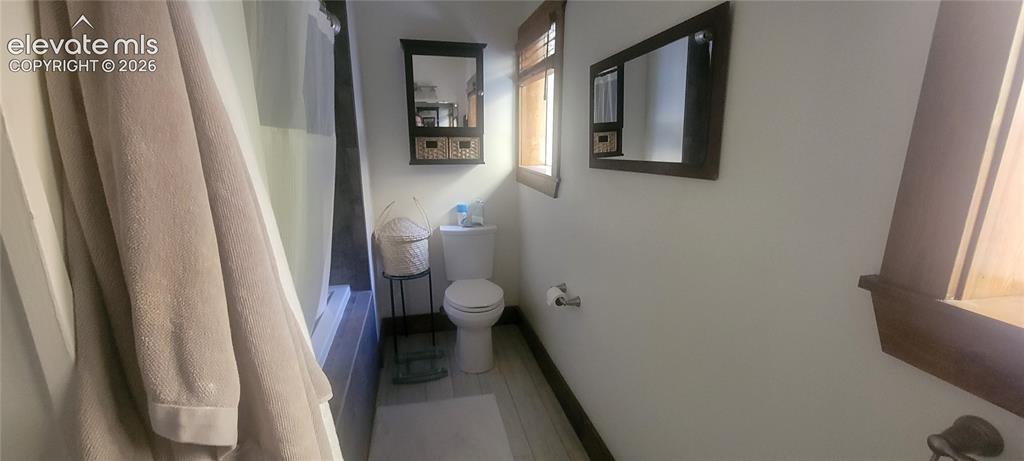 Image 13 of 27: Bathroom featuring a built-in tub with shower, wood-finish flooring, and a