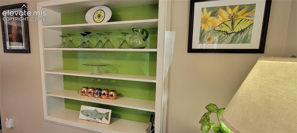 Image 14 of 30: Built-in shelving unit with white shelves and a vibrant green back panel