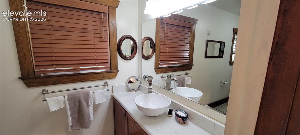 Image 19 of 30: Bathroom vanity featuring a vessel sink, single-handle faucet, and white co