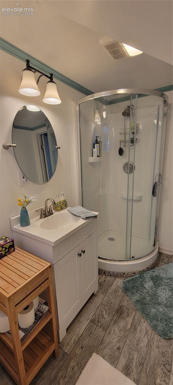 Image 22 of 30: Downstairs bathroom featuring a glass-enclosed corner shower, white vanity
