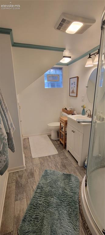 Image 23 of 30: Downstairs bathroom featuring a glass-enclosed corner shower, white vanity