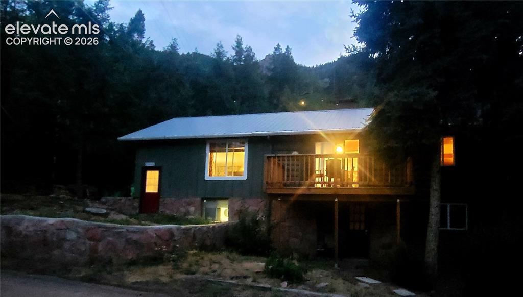 Image 27 of 30: Exterior featuring a metal roof, a wood deck with railings, stone-clad lowe