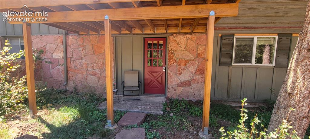 Image 3 of 30: Downstairs has seperate entry.Covered entry with natural wood posts, red pa