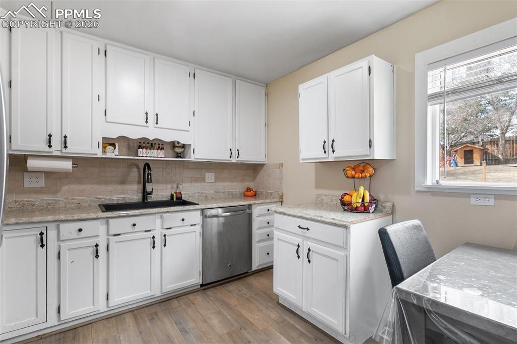 Image 10 of 29: Kitchen with white cabinets, dishwasher, open shelves, light wood finished 
