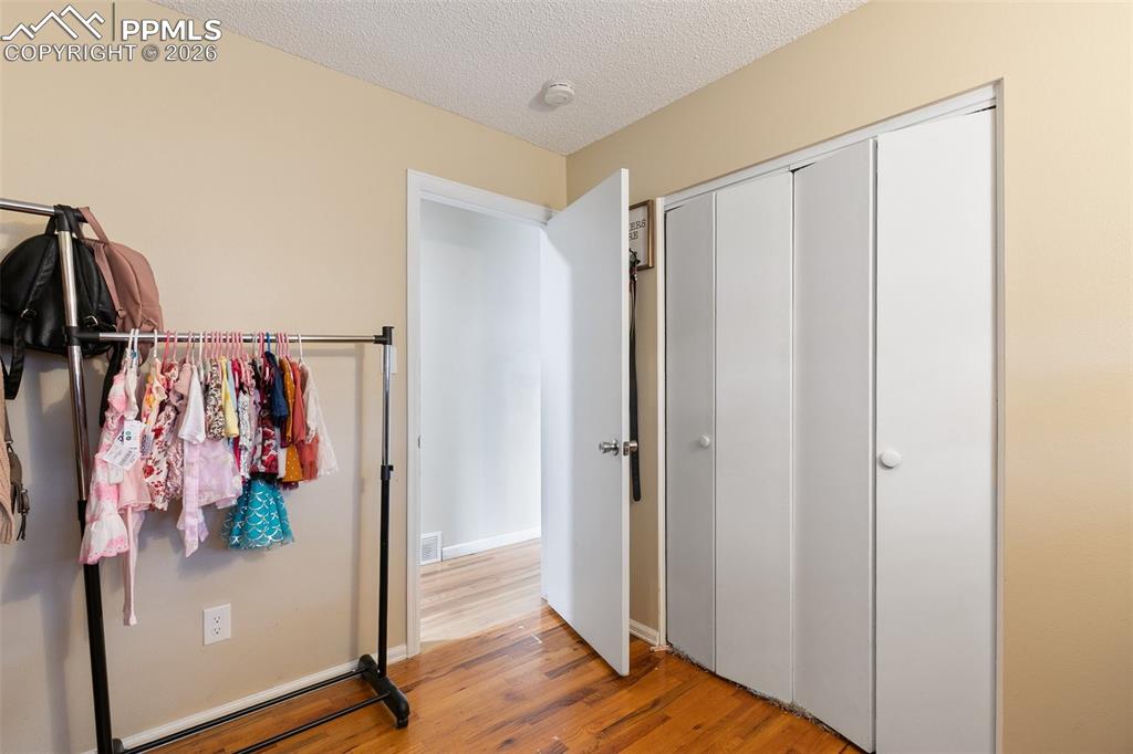 Image 18 of 29: Bedroom featuring a textured ceiling, light wood-style floors, and a closet