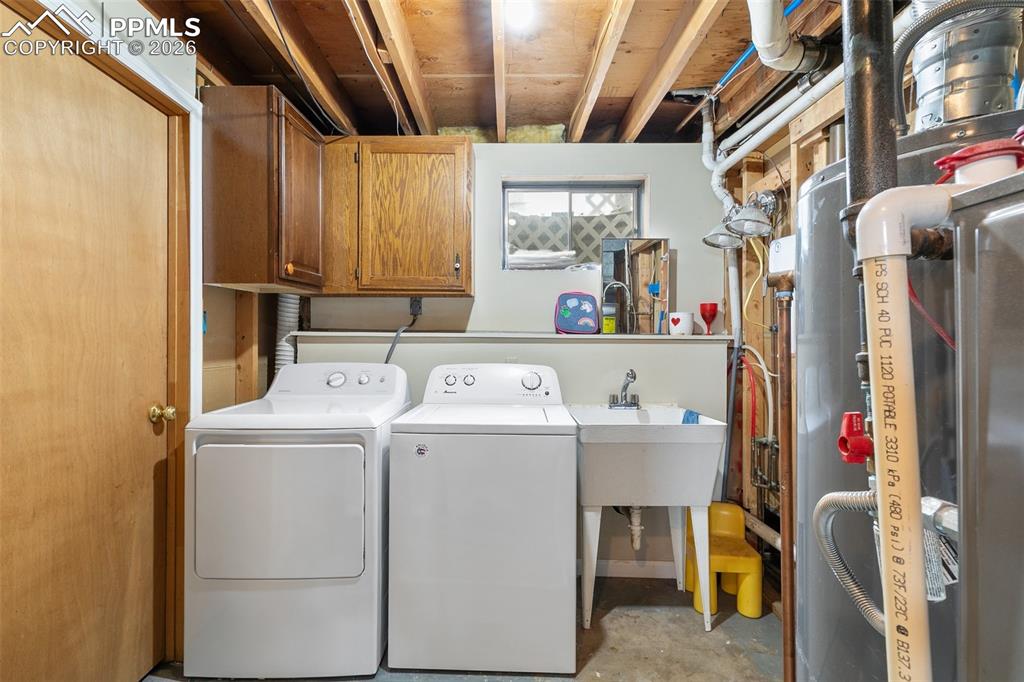 Image 27 of 29: Laundry area with cabinet space, unfinished concrete floors, washer and dry
