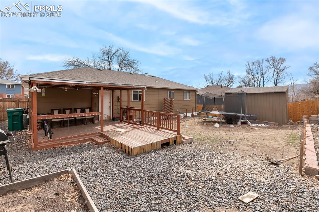 Image 29 of 29: Rear view of property featuring a trampoline, a wooden deck, and roof with 