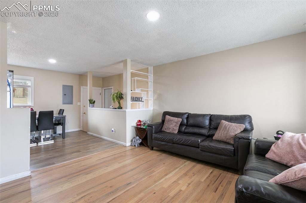 Image 4 of 29: Living area with wood finished floors, a textured ceiling, recessed lightin