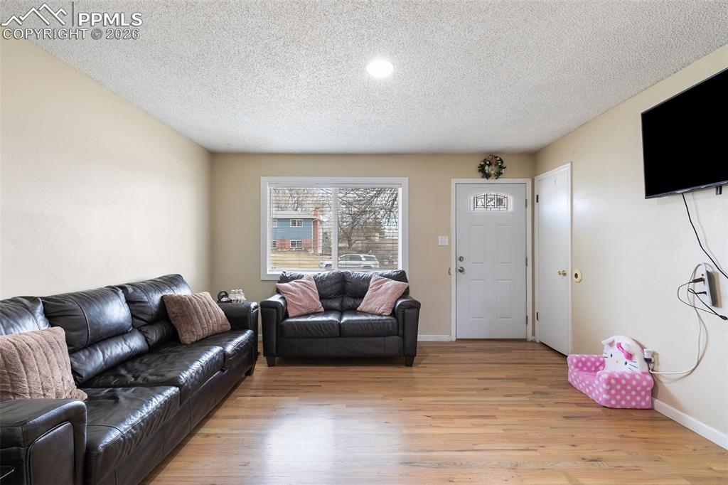 Image 6 of 29: Living room featuring a textured ceiling and light wood-style floors