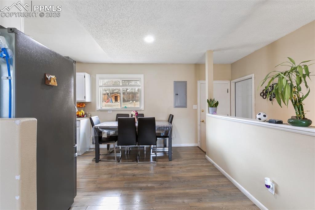 Image 7 of 29: Dining area with dark wood-type flooring, electric panel, a textured ceilin
