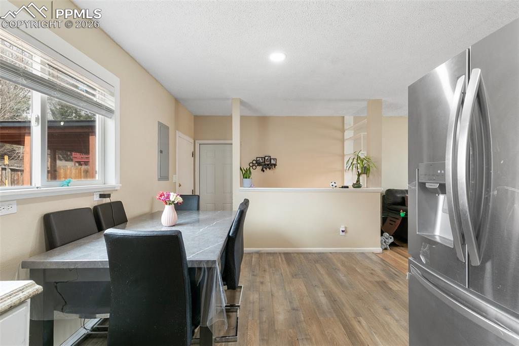 Image 8 of 29: Dining area with light wood-style floors and a textured ceiling