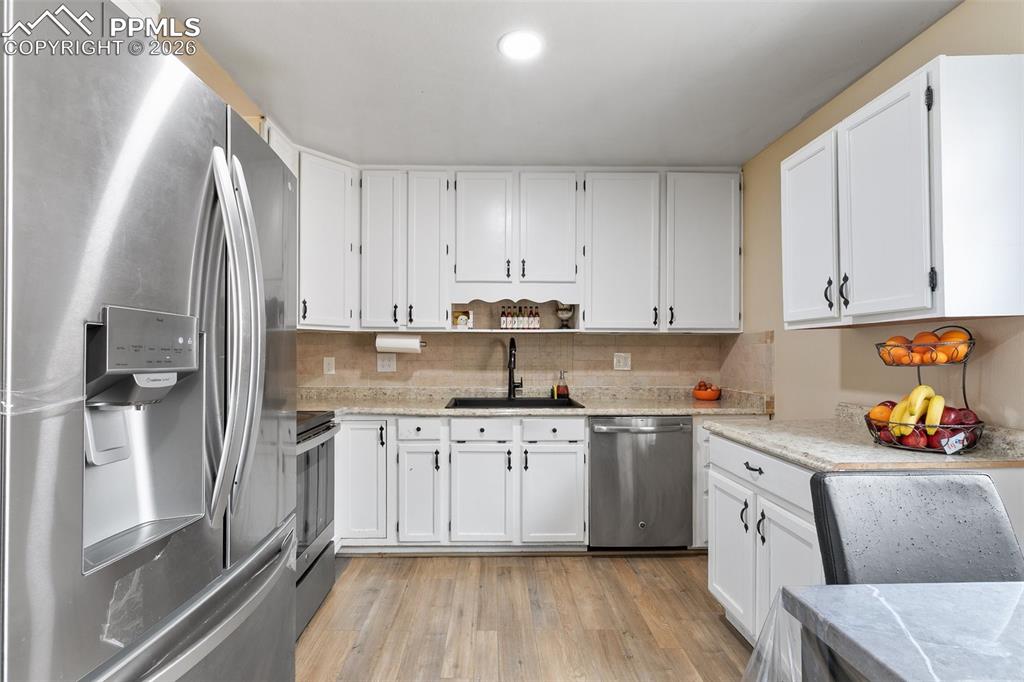 Image 9 of 29: Kitchen featuring stainless steel appliances, white cabinets, and light woo