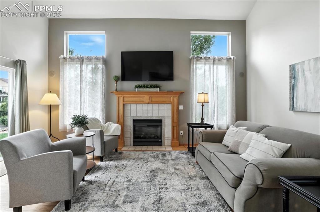 Image 12 of 41: Main floor living room with cozy fireplace, large windows overlooking the b