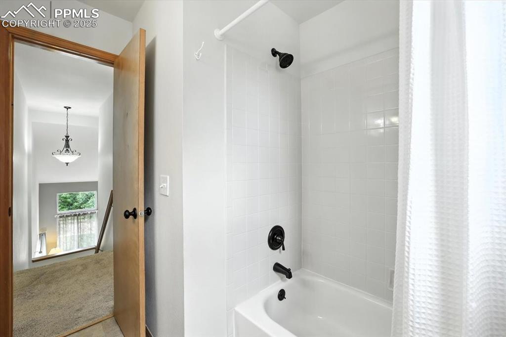 Image 22 of 41: Hall bath features tiled shower surround and updated fixures