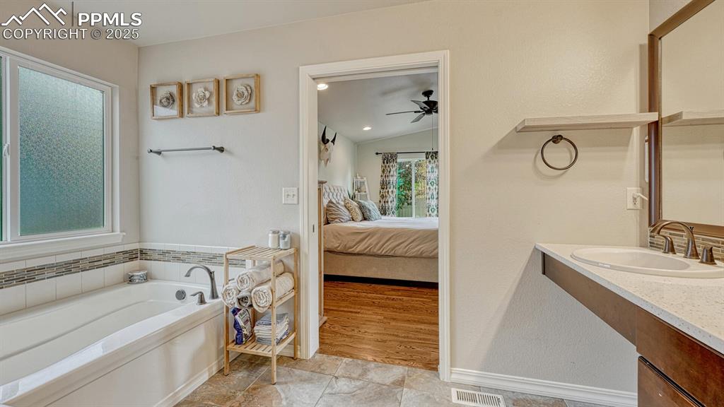 Image 18 of 44: Bathroom featuring a garden tub, vanity, lofted ceiling, ensuite bath, and 