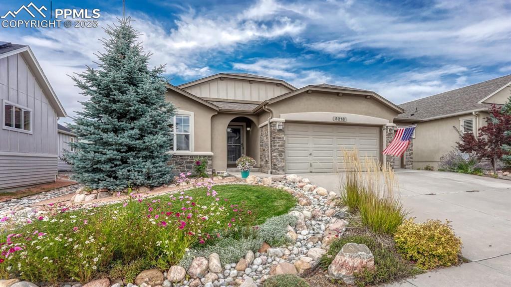 Image 2 of 44: View of front of property featuring driveway, stone siding, an attached gar