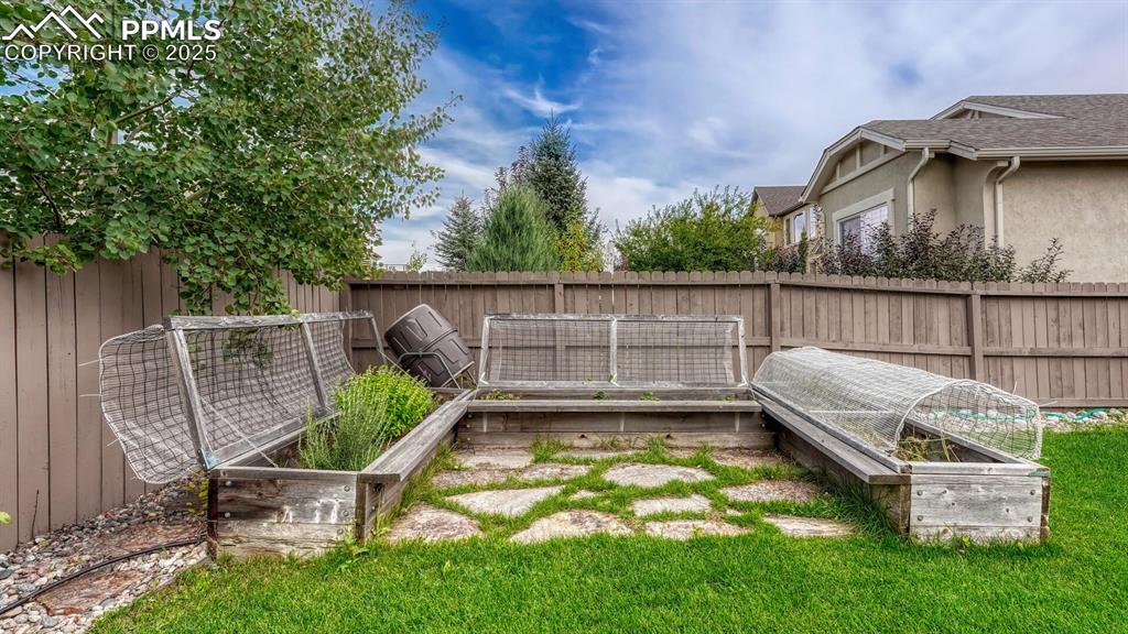 Image 25 of 44: Fenced backyard with a vegetable garden