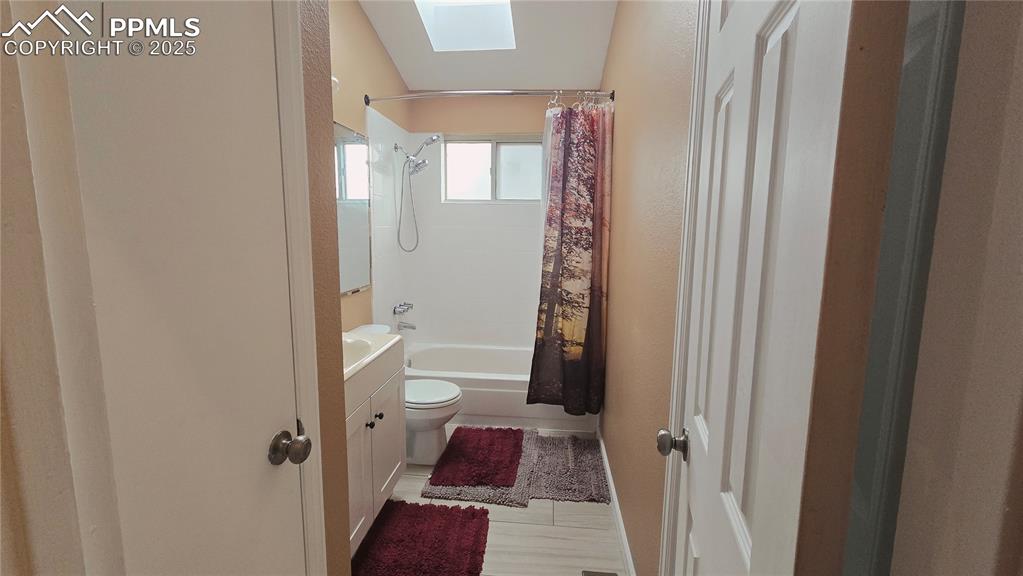 Image 14 of 42: Full bathroom featuring shower / bath combo, vanity, a skylight, and new ti