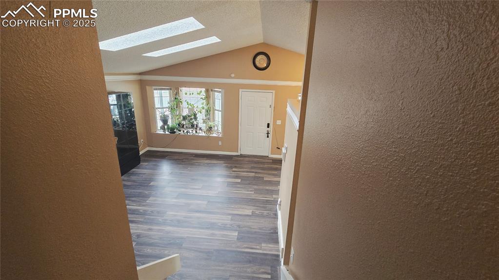 Image 26 of 42: Entryway featuring lofted ceiling, a textured wall, dark wood-type flooring