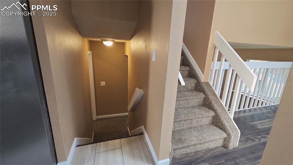 Image 27 of 42: Stairway featuring a textured wall and wood finished floors
