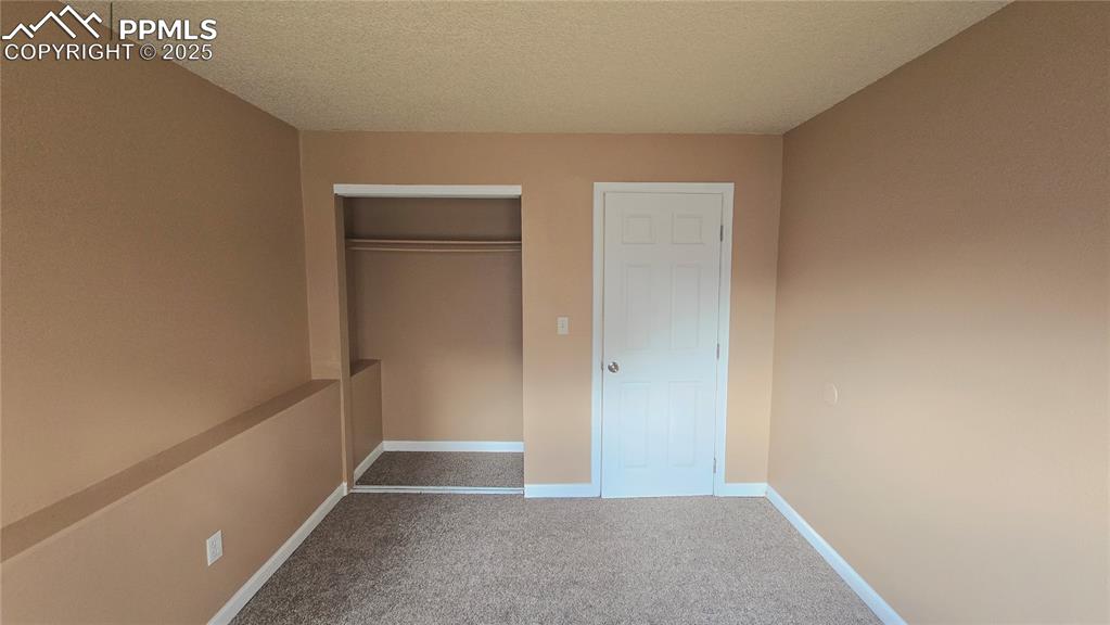 Image 38 of 42: Unfurnished bedroom with carpet floors, a textured ceiling, and a closet