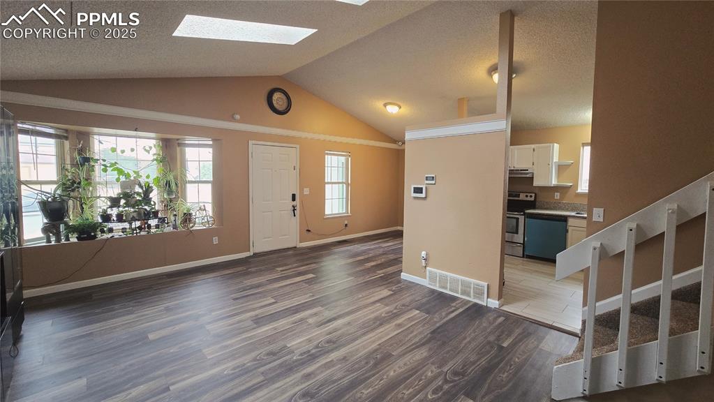 Image 4 of 42: Entryway featuring dark wood-style flooring, lofted ceiling, plenty of natu