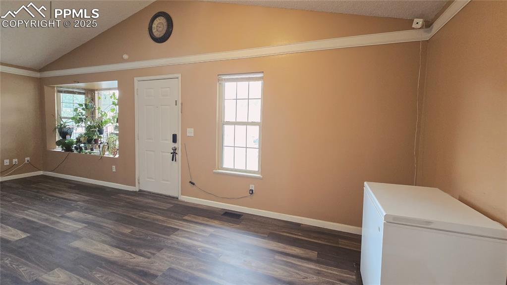 Image 6 of 42: Entryway featuring vaulted ceiling and dark wood-type laminate flooring