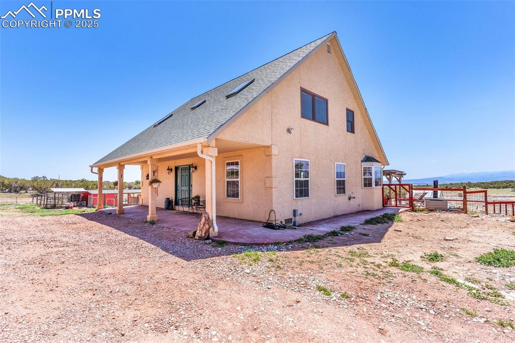 Image 4 of 49: Rear view of house featuring stucco siding, fence, a patio, and a shingled 