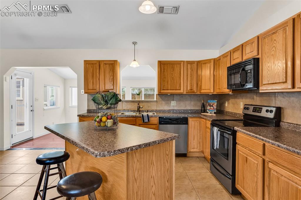 Image 12 of 42: Kitchen with appliances with stainless steel finishes, light tile patterned