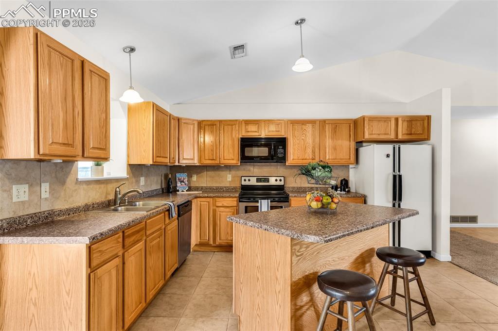 Image 13 of 42: Kitchen featuring appliances with stainless steel finishes, vaulted ceiling
