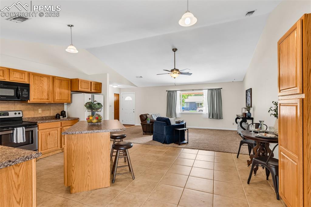 Image 15 of 42: Kitchen with stainless steel electric range, black microwave, freestanding 
