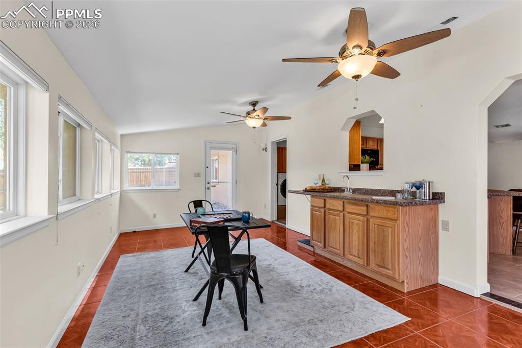 Image 17 of 42: Dining area with dark tile patterned flooring, ceiling fan, lofted ceiling,