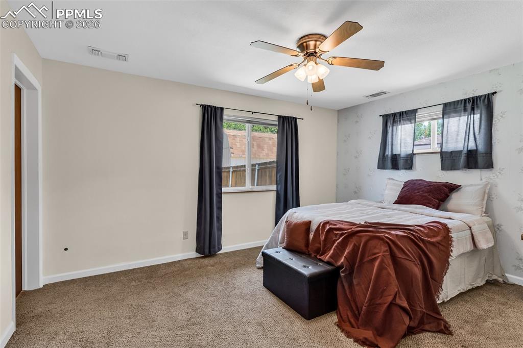 Image 19 of 42: Bedroom with multiple windows, carpet floors, and ceiling fan