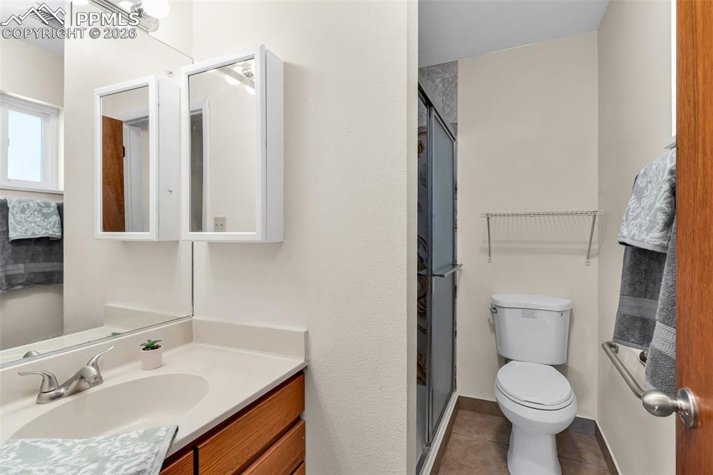 Image 26 of 42: Bathroom featuring toilet, a stall shower, tile patterned floors, and vanit