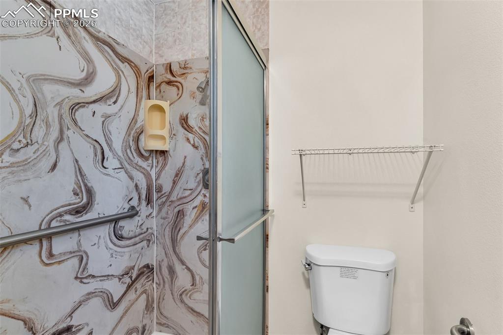 Image 27 of 42: Bathroom featuring a shower with shower door and toilet